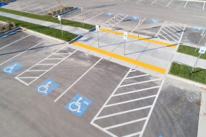 Overhead color photo of a set of six accessible parking spaces, adjacent access aisles, and signage.